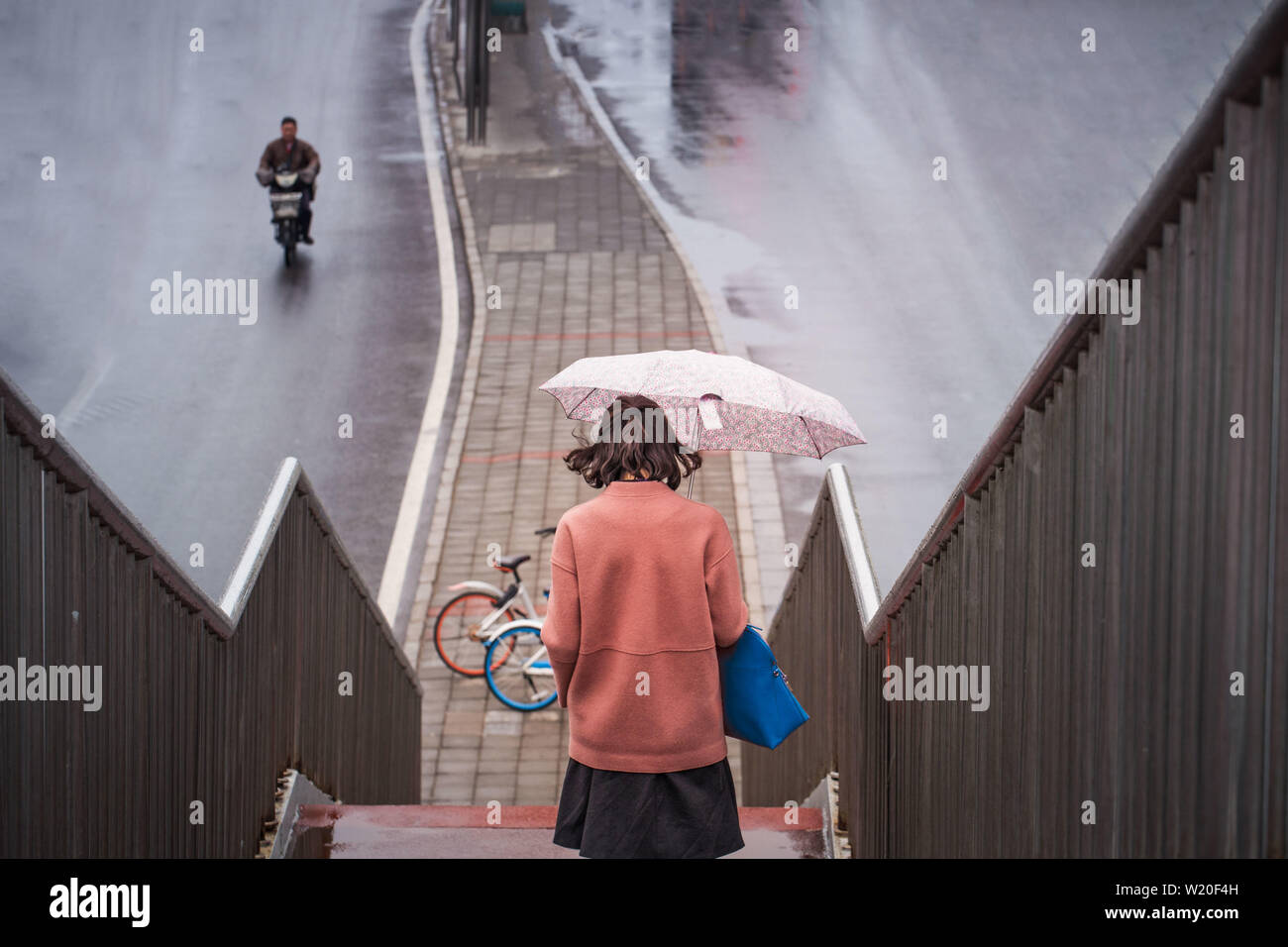 Ragazza camminare giù dal ponte del piede durante la giornata piovosa a Pechino Foto Stock