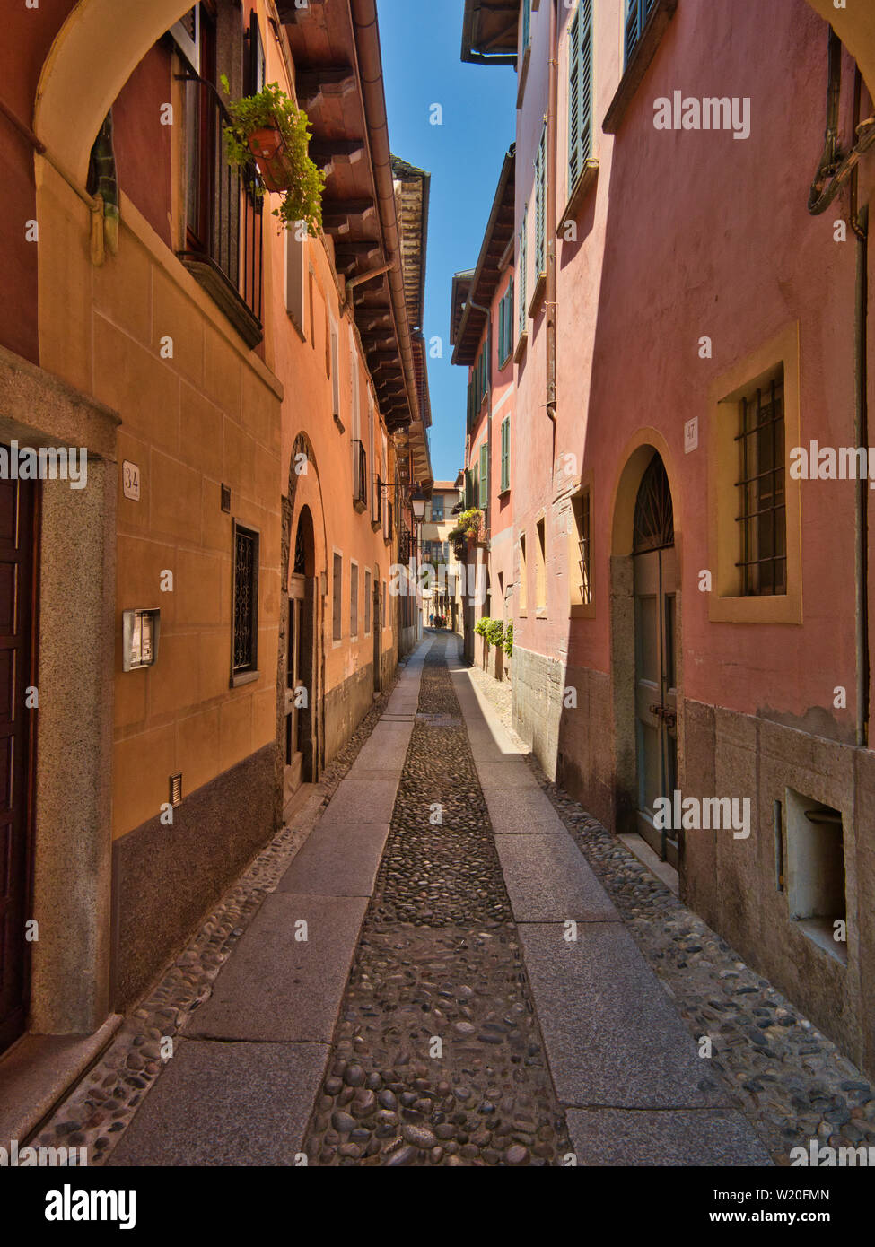 E la stretta strada a ciottoli del borgo di Orta San Giulio Italia per una serata estiva Foto Stock