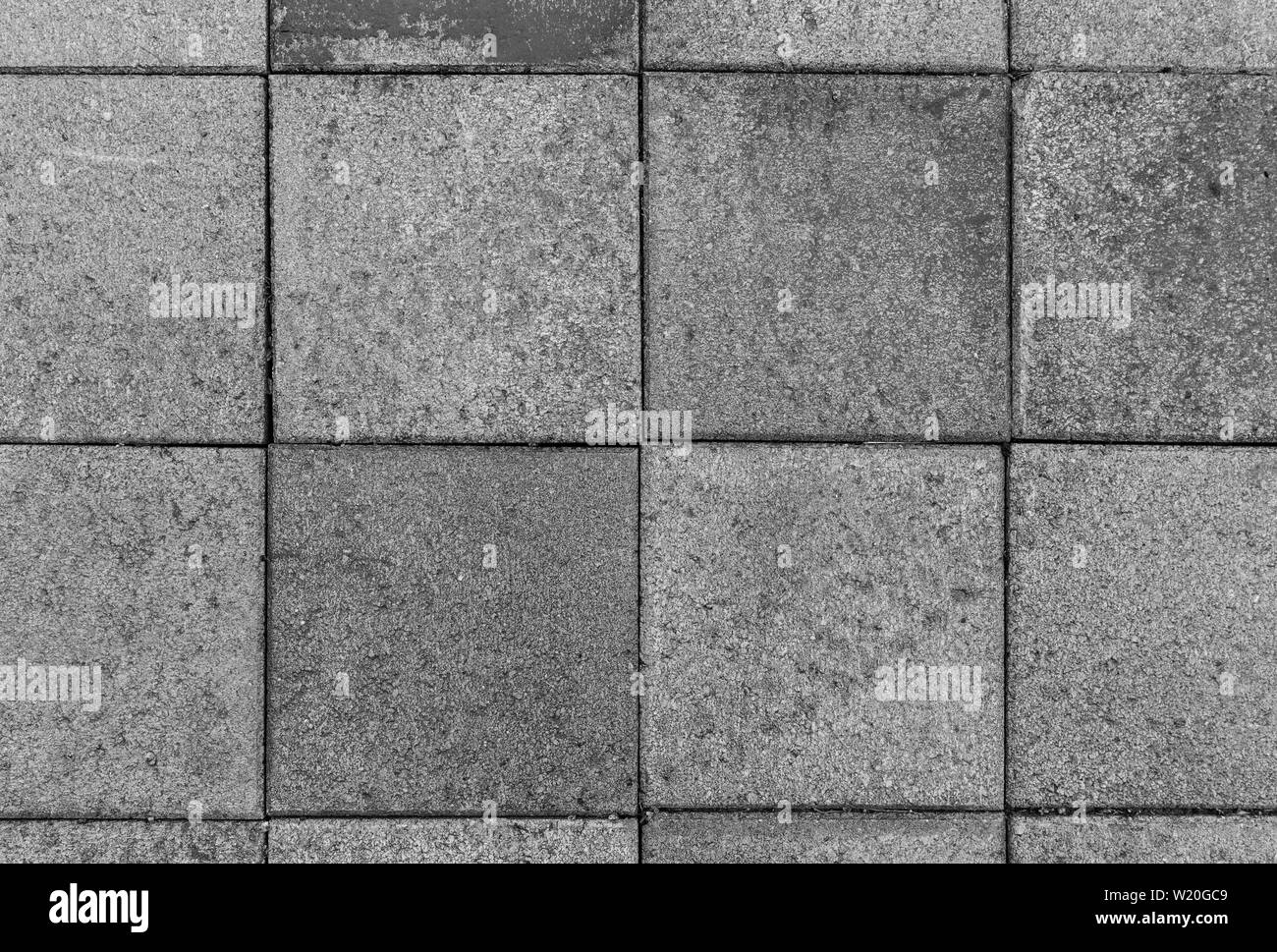 Close-up di un po' sporca e weathered square pietre per pavimentazione o blocchi esterni visto dal di sopra in bianco e nero. Alta risoluzione sfondo a trama. Foto Stock