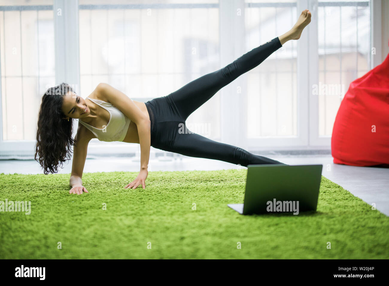 Slim donna nella posizione del cobra pongono alla classe di yoga, Vasisthasana esercizio a casa Foto Stock