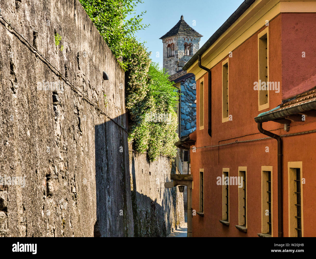 Strada desolata con via e pareti di pietra sull'Isola di San Giulio nel Lago d'Orta con il campanile di San Giulio Basilica in background durante una Foto Stock