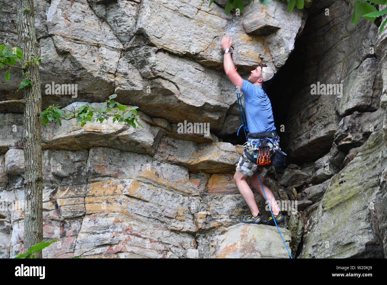 Un giovane maschio scalatore lavora il suo modo di una scogliera a battuta la molla Trail a Pilot Mountain State Park in North Carolina. Foto Stock