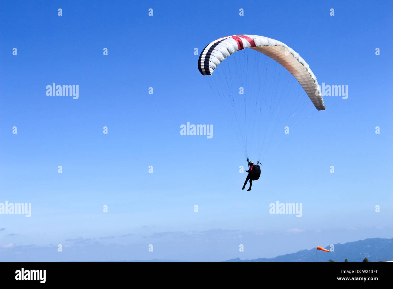 Parapendio vola nel cielo blu sul paesaggio delle valli in Indonesia Foto Stock