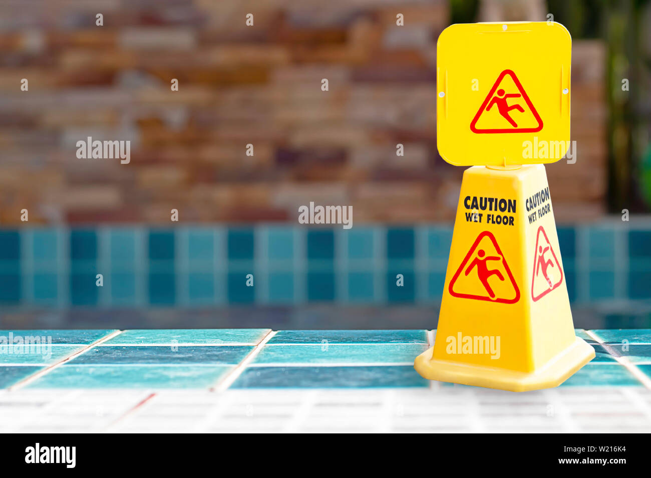 Targhette di avvertimento pavimento bagnato accanto alla piscina fatta di plastica gialla. Foto Stock