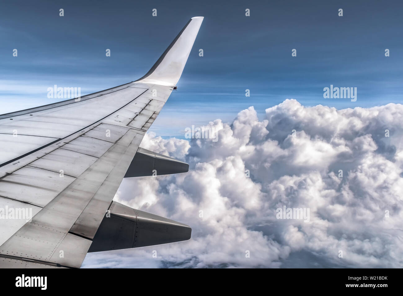 Vista stupefacente di nuvole drammatico da finestra laterale del sedile di aereo. Le ali con tutti i suoi componenti sono visibili. Le nubi sono soffici come palline di cotone. Foto Stock