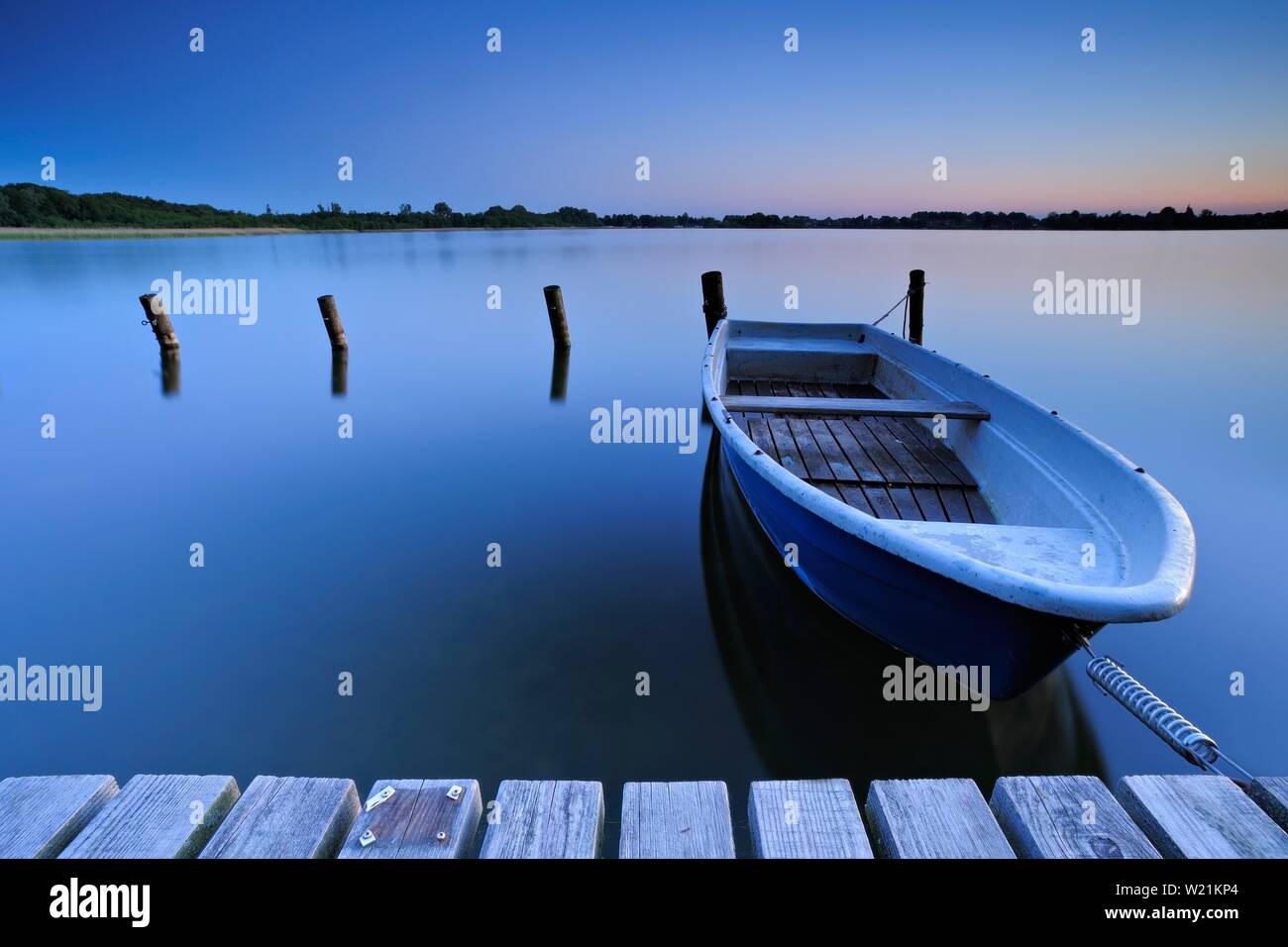Pontile di sbarco con barca a remi, silenzioso Lago al tramonto, Lago Schaalsee, Meclemburgo-Pomerania, Germania Foto Stock