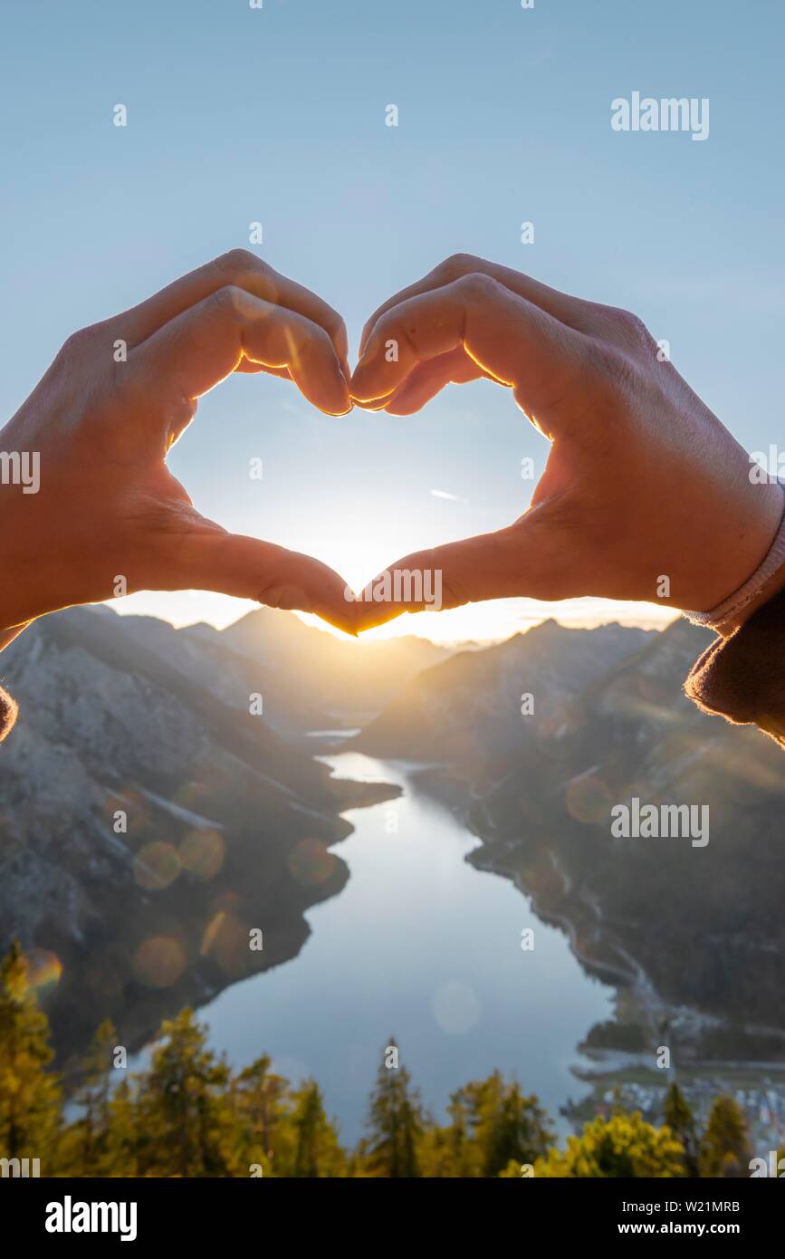 Forme a mano un cuore di fronte le Alpi ed il lago di montagna, simbolo di amore per la natura e per escursionismo, vista da Schonjochl, Plansee, Tirolo, Austria Foto Stock