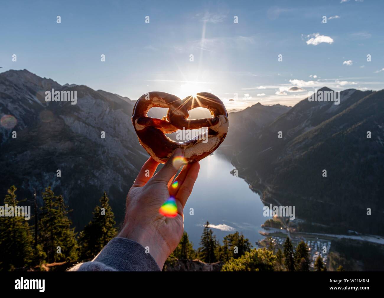 Mano azienda pretzel bavarese nella parte anteriore del panorama alpino, vista da Schonjochl al Plansee, Tirolo, Austria Foto Stock