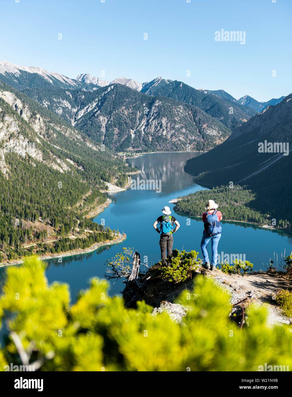 Due escursionisti guardando in lontananza sul lago Plansee, circondato da montagne, Schonjochl, Plansee, Tirolo, Austria all'indietro. Foto Stock