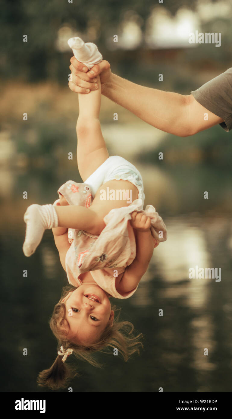 La mano del padre tiene la sua figlia piccola testa rivolta verso il basso accanto al lago. Foto Stock
