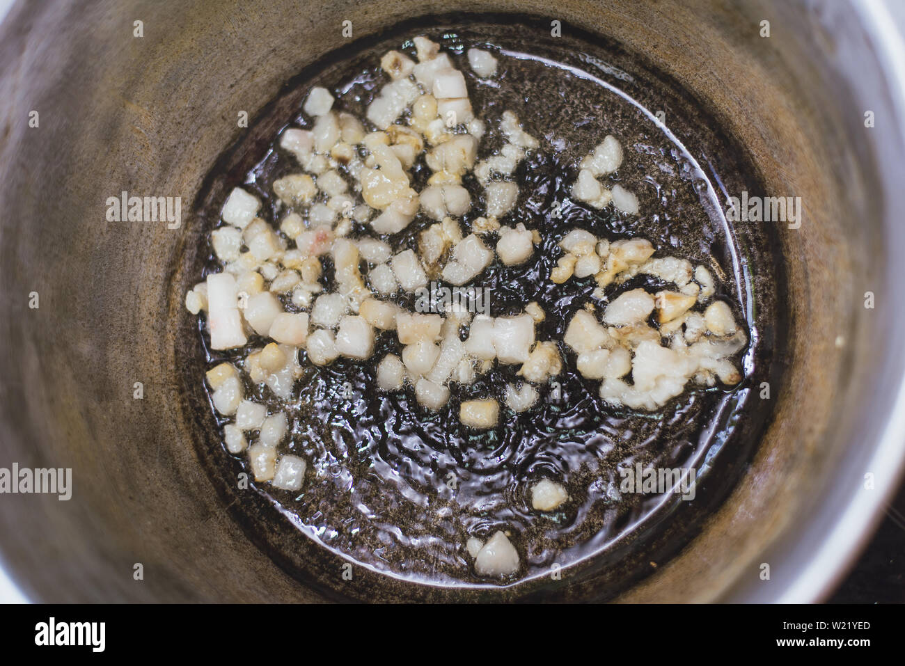 Grasso per friggere la coda in un paiolo di rame sul fornello. Il riscaldamento del lardo in padella. Foto Stock