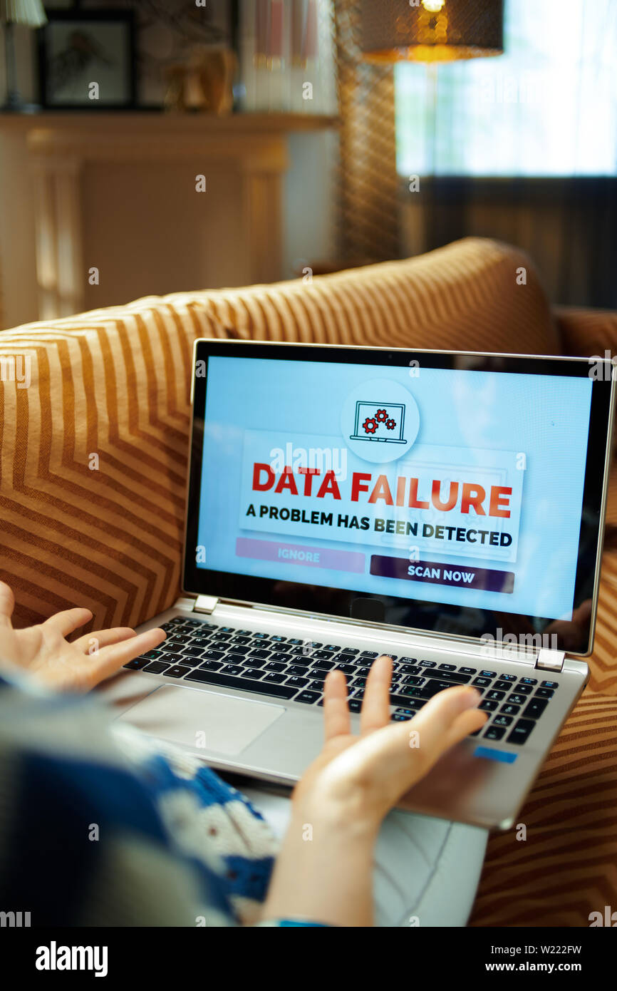 Infastiditi donna moderna seduti sul divano del soggiorno moderno nella soleggiata caldo giorno d'estate avente il problema su un pc Foto Stock