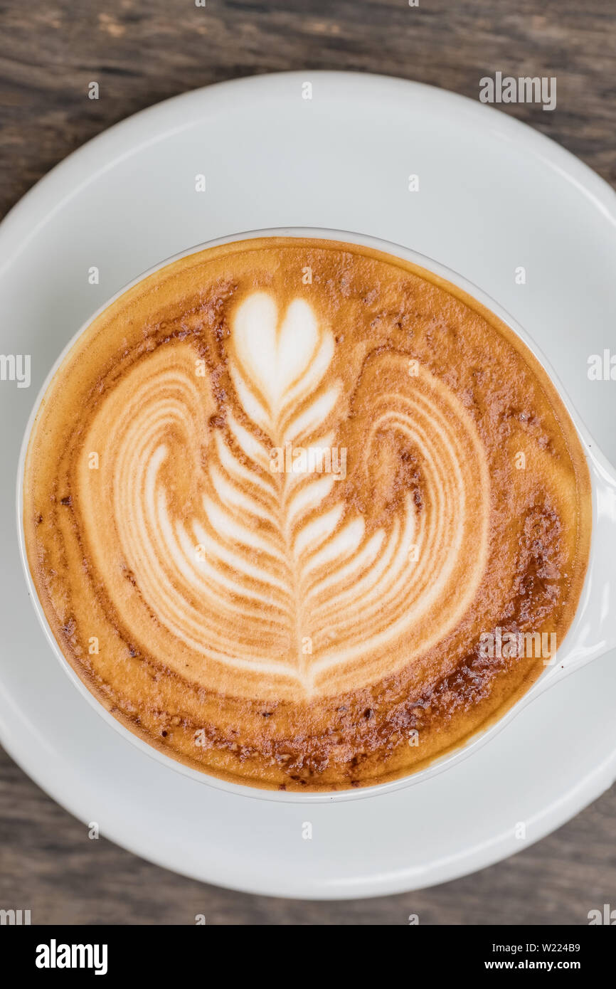 Tazza di caffè cappuccino con belle latte art servita su un tavolo di legno. Foto Stock