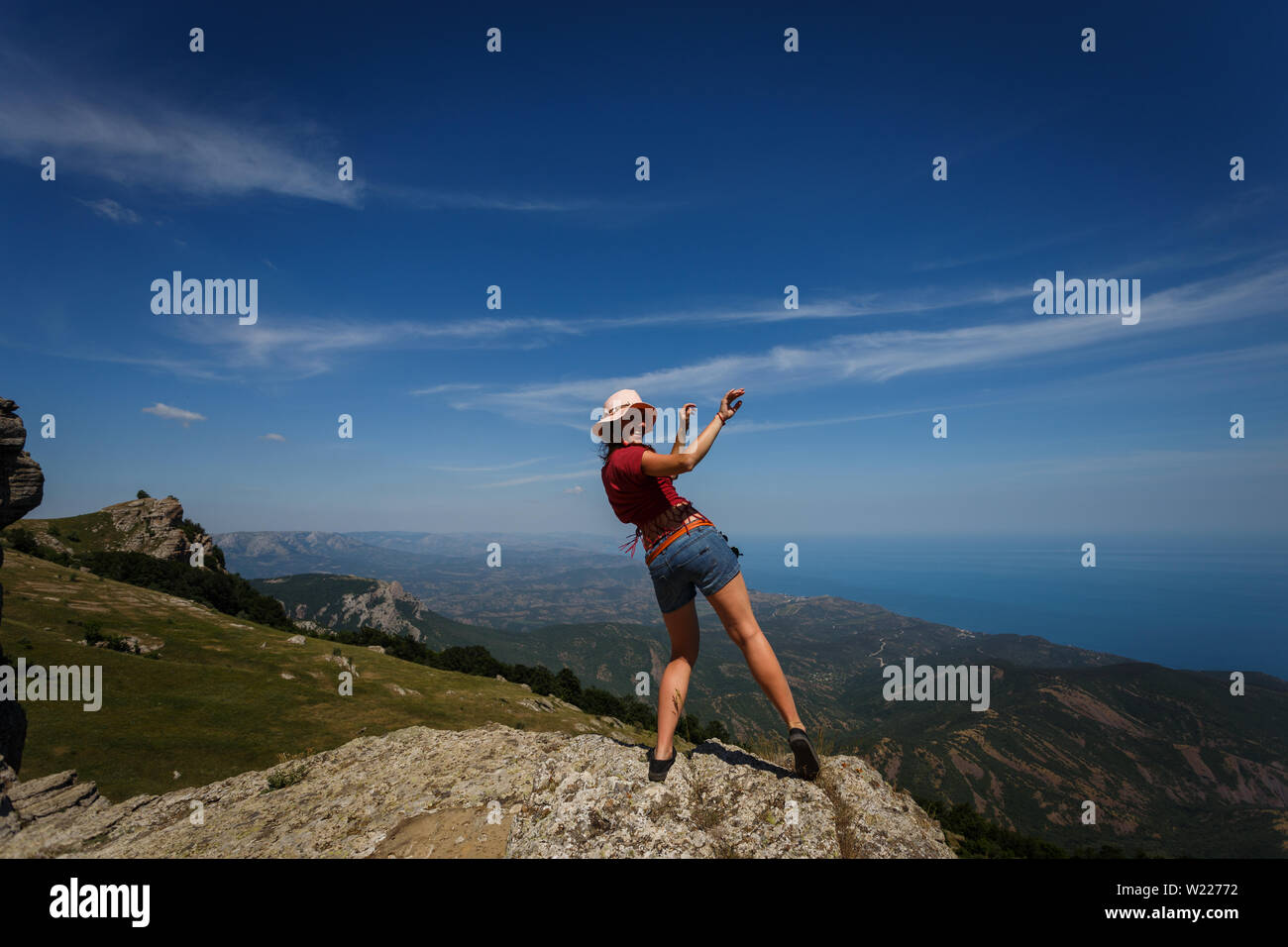 Donna felice in pantaloncini corti e indossando un cappello sta ballando  sulla cima di una montagna. Il concetto di libertà, ricreazione, viaggi.  Buona fortuna e successo Foto stock - Alamy