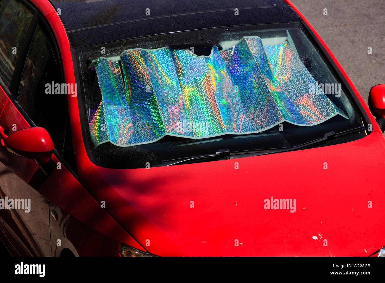 Parabrezza Irridescent deflettore di calore in un caldo rosso auto. Cipro. 2019 Foto Stock
