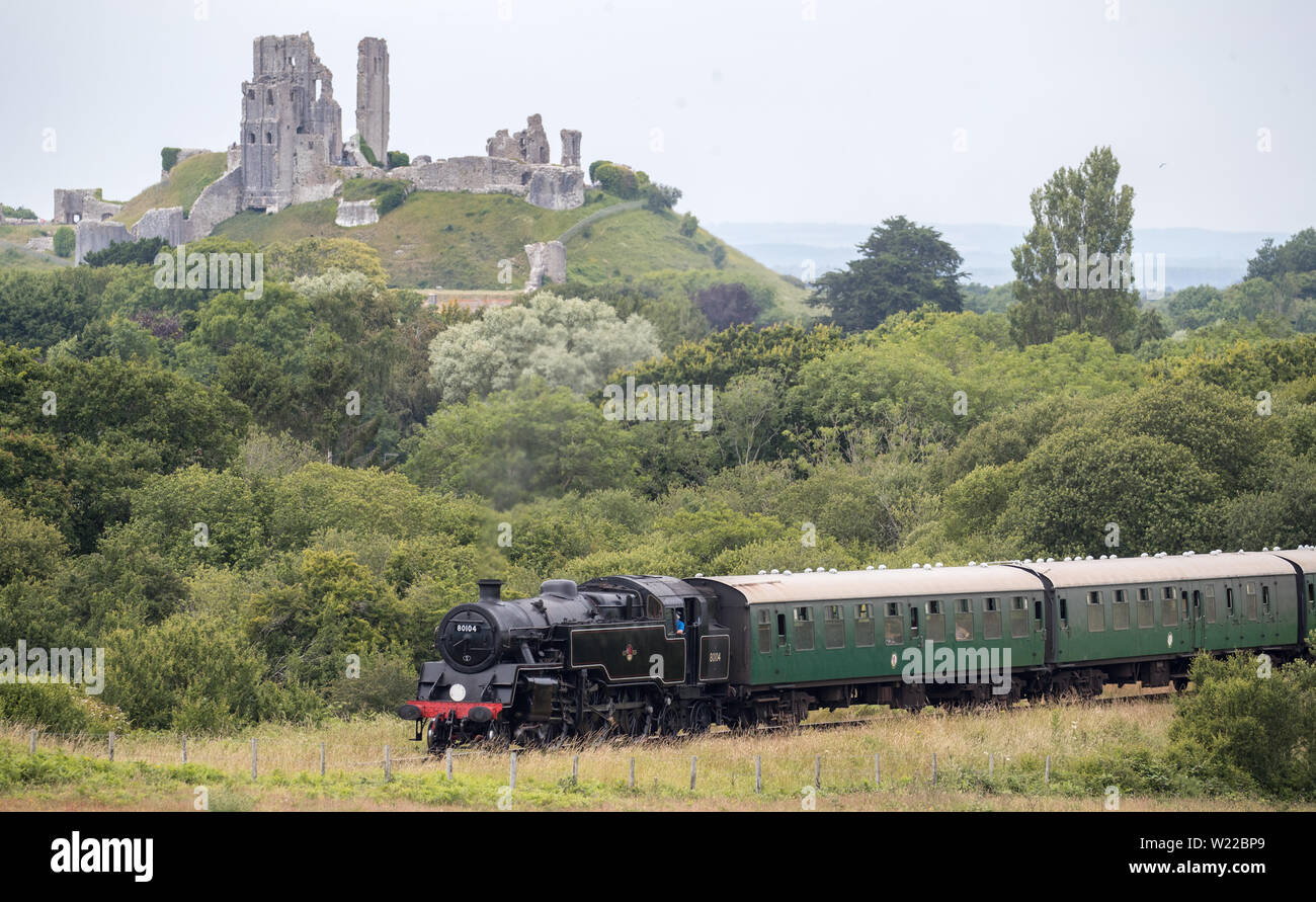 Locomotiva a vapore BR Standard Classe 4 80104, rende il modo in passato Corfe Castle come si muove lungo la ferrovia a Swanage nel Dorset. Foto Stock