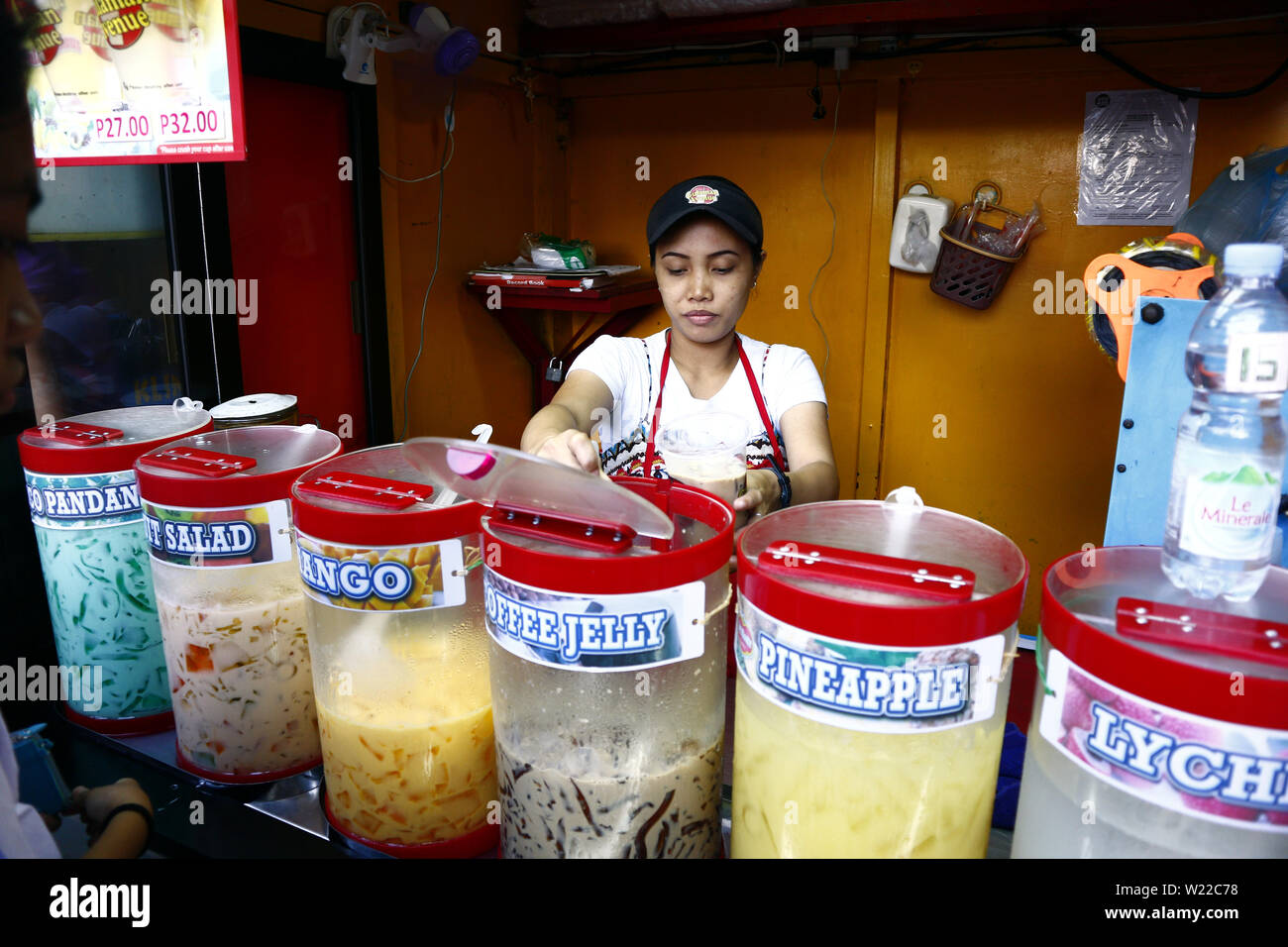 ANTIPOLO City, Filippine - luglio 3, 2019: un lavoratore a un succo di frutta stand prepara un ordine per un cliente. Foto Stock