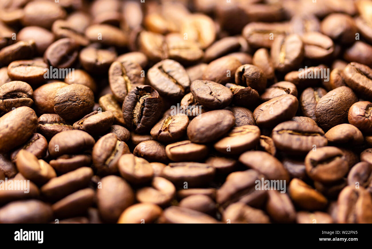 Pila di chicchi di caffè texture, vicino, sfondo scuro, profondità di campo Foto Stock