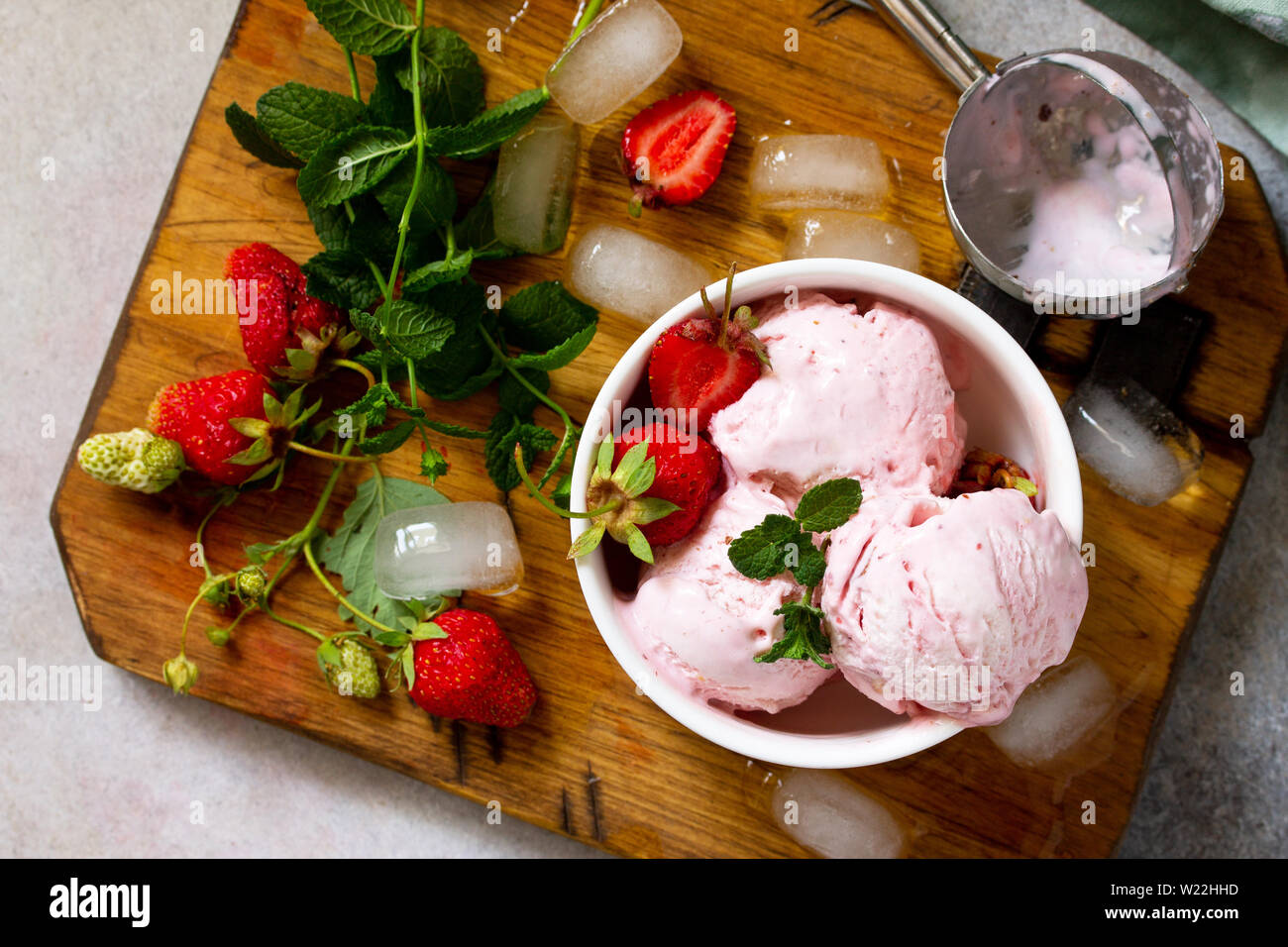 Gelato alla fragola in bianco ciotola su una pietra di luce o tavola di ardesia. Spazio libero per il tuo testo. Foto Stock