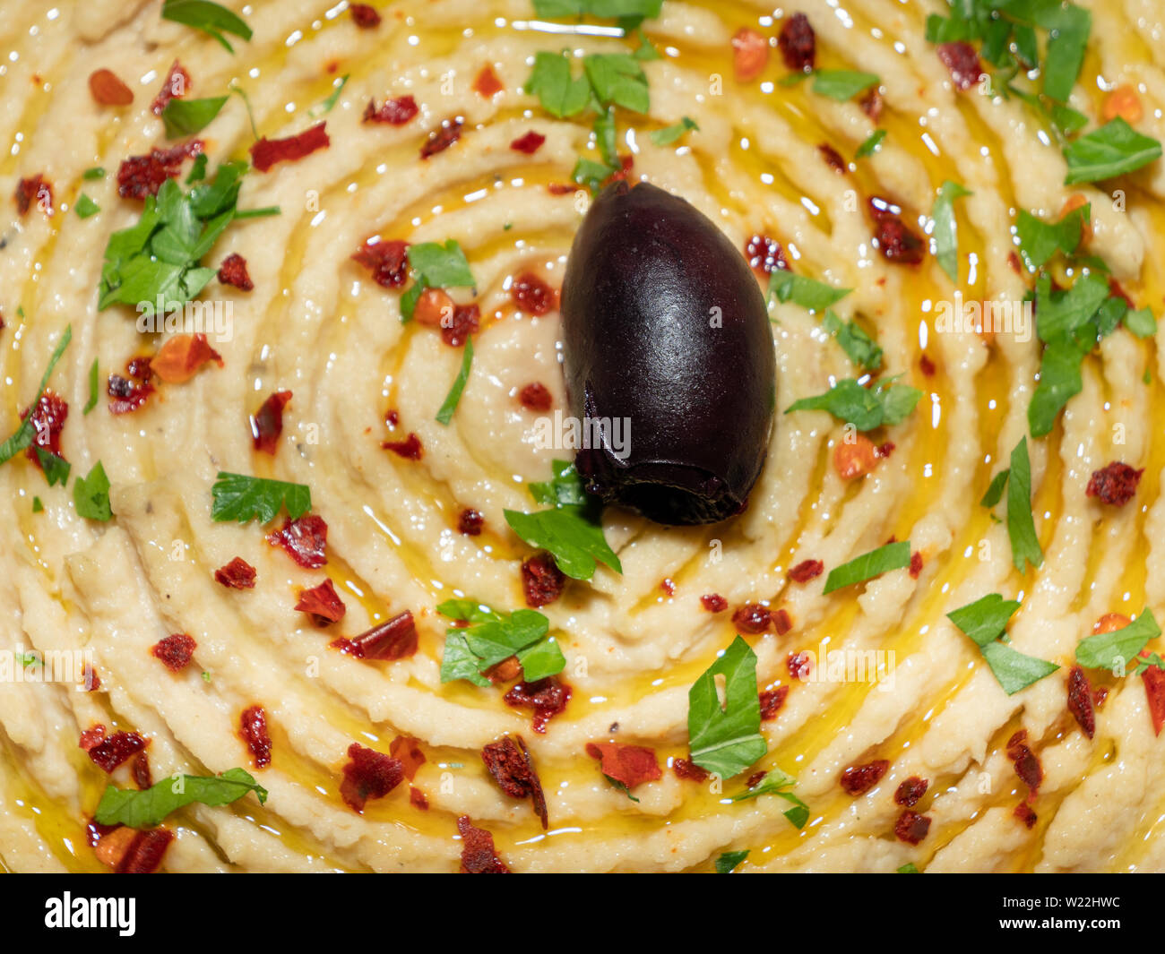 Hummus guarnita con Olive, fiocchi di pepe e prezzemolo tritato. Oriental, turco aperitivo o antipasto chiamato meze. Foto Stock