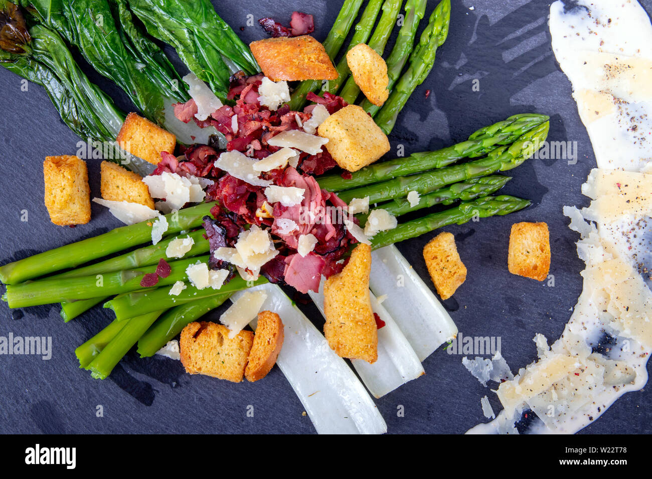 Caesar asparagi con fette di formaggio parmigiano, carne affumicata e crouton cucina gourmet piatto Foto Stock