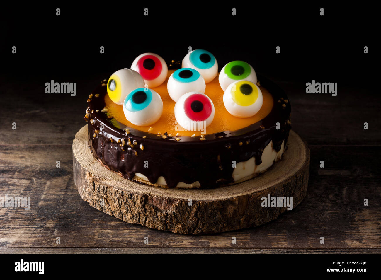 Torta di Halloween con la caramella occhi decorazione su un tavolo di legno e sfondo nero Foto Stock