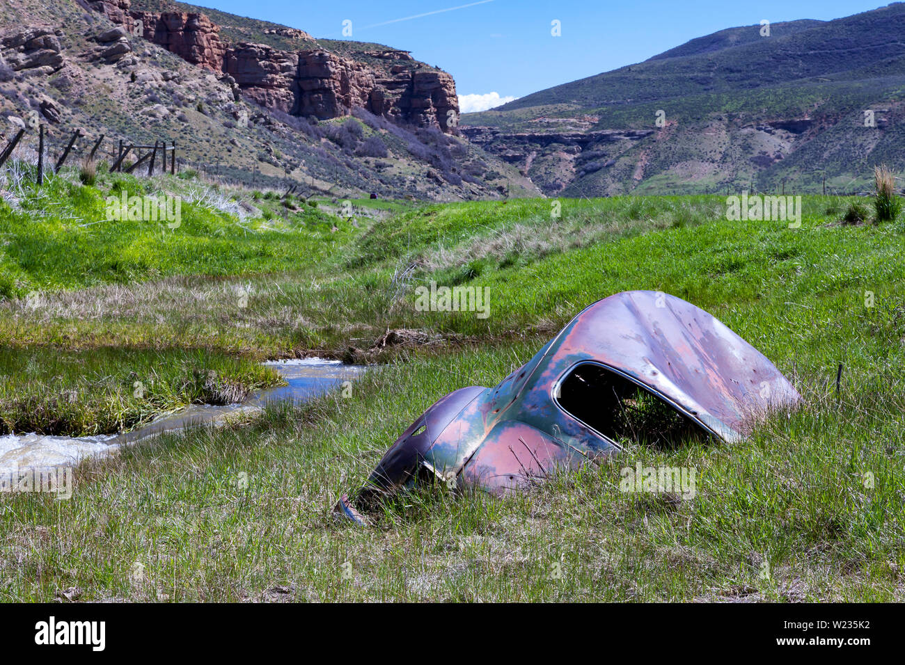 Un 1946 Plymouth Deluxe 2 porta berlina è parzialmente immerso nel letto del torrente di Echo Creek in Echo Canyon lungo il Lincoln Highway in Eastern Utah. Foto Stock