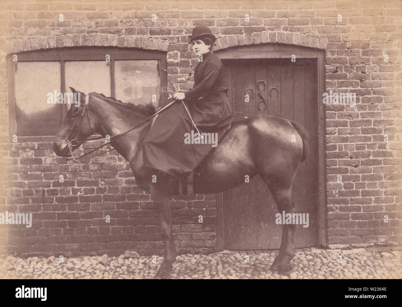 Victorian fine 1880 / inizio 1890 fotografia di un quartiere alla moda di Lady seduto su un cavallo in un cantiere stabile. Foto Stock