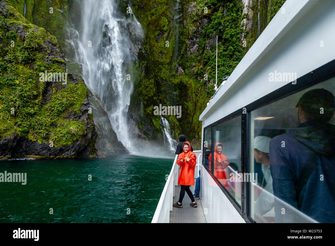 A Milford Sound barca si avvicina una cascata, il Parco Nazionale di Fiordland, Isola del Sud, Nuova Zelanda Foto Stock