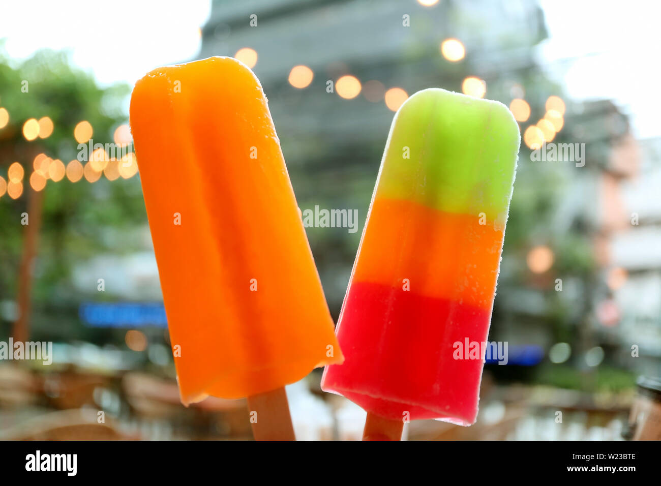 Coppia di frutta mix popsicles con sfocata urbano vista serale Foto Stock