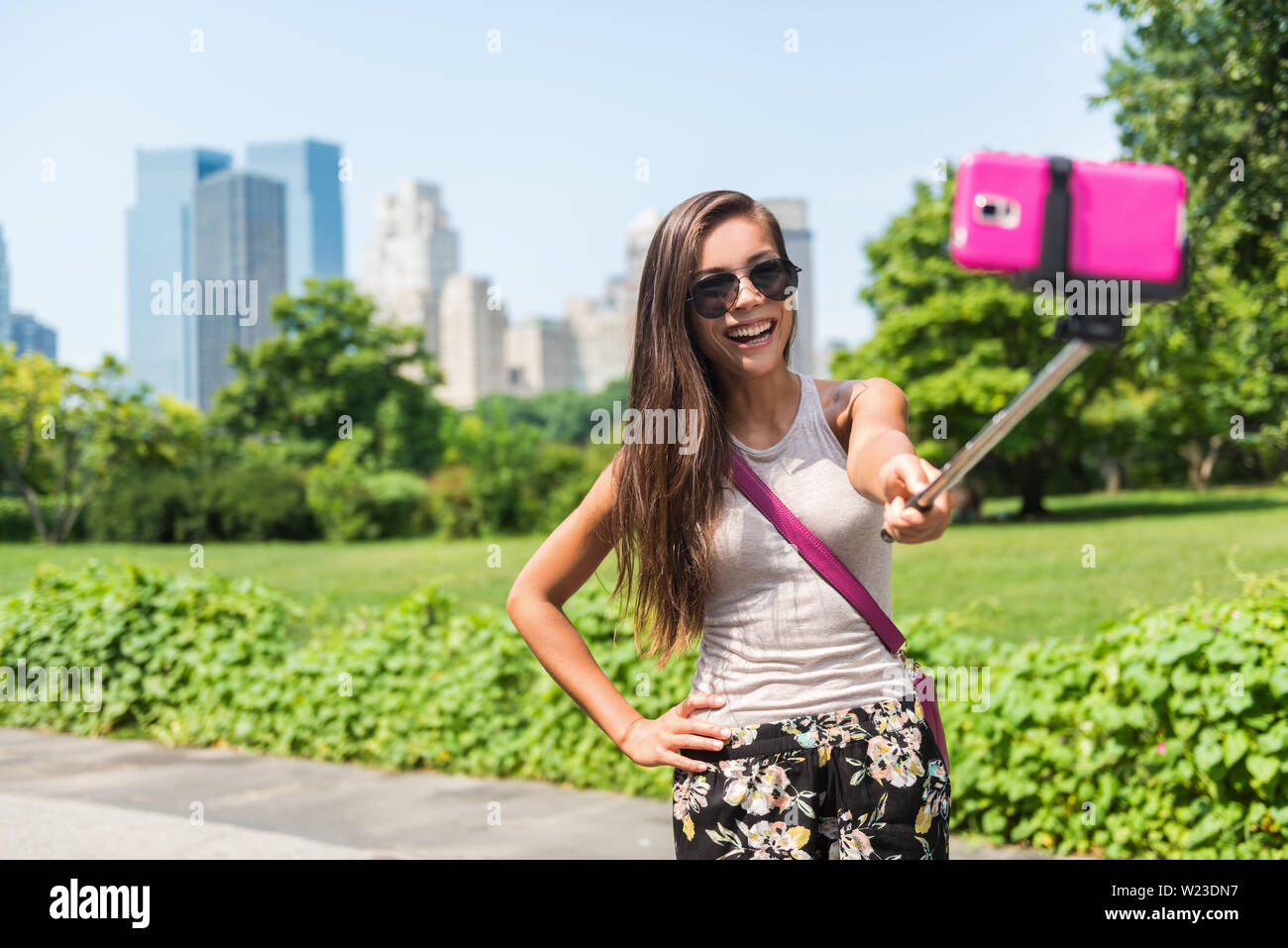 Buon viaggio turistica prendendo Self-portrait foto con il telefono cellulare e selfie stick in una popolare attrazione di New York. Central park donna passeggiate in estate Park di New York City, Manhattan STATI UNITI D'AMERICA. Foto Stock