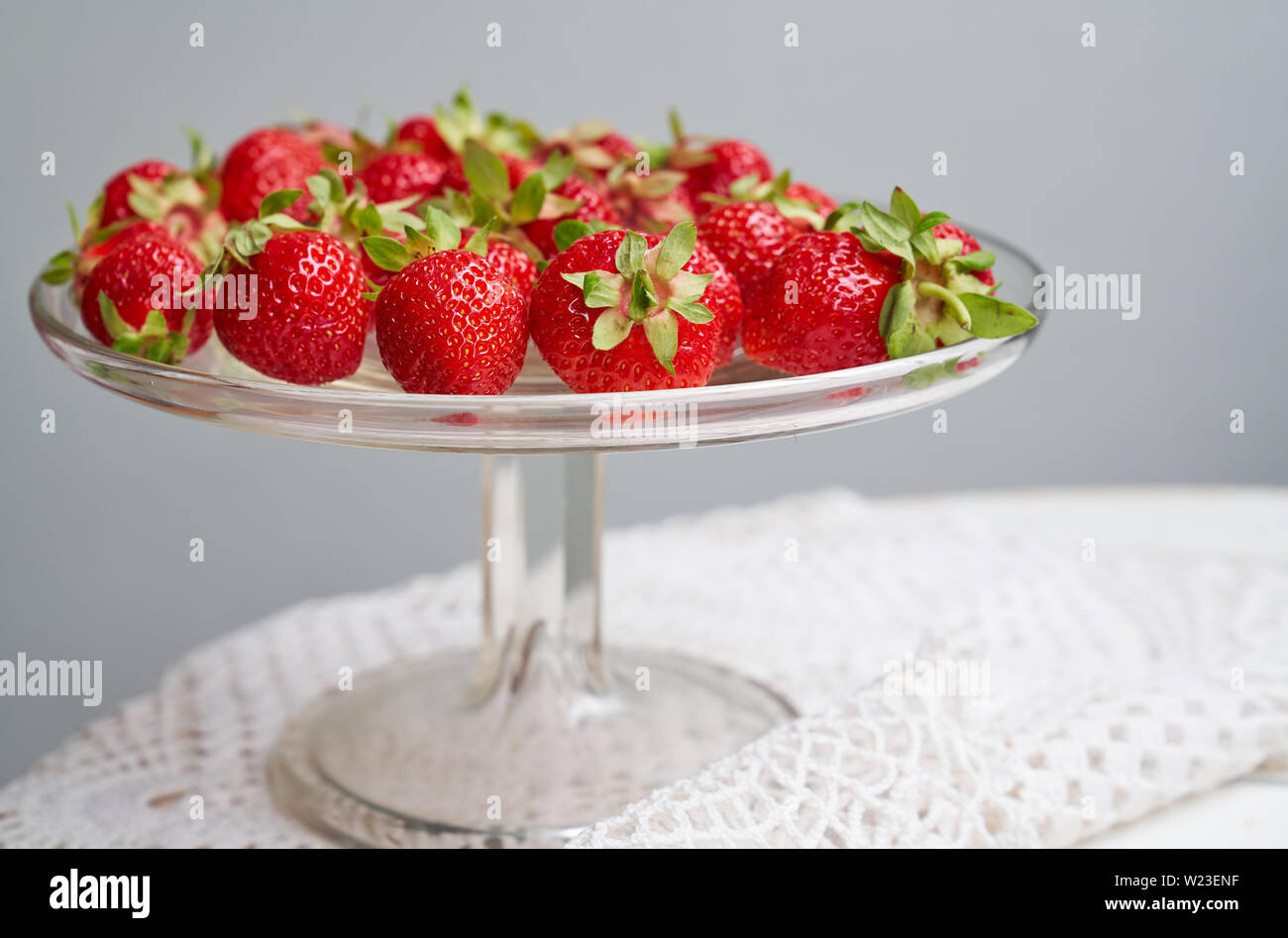 Rosso fresco Fragole sulla lastra di vetro sulla tavola con tovaglia di pizzo Foto Stock