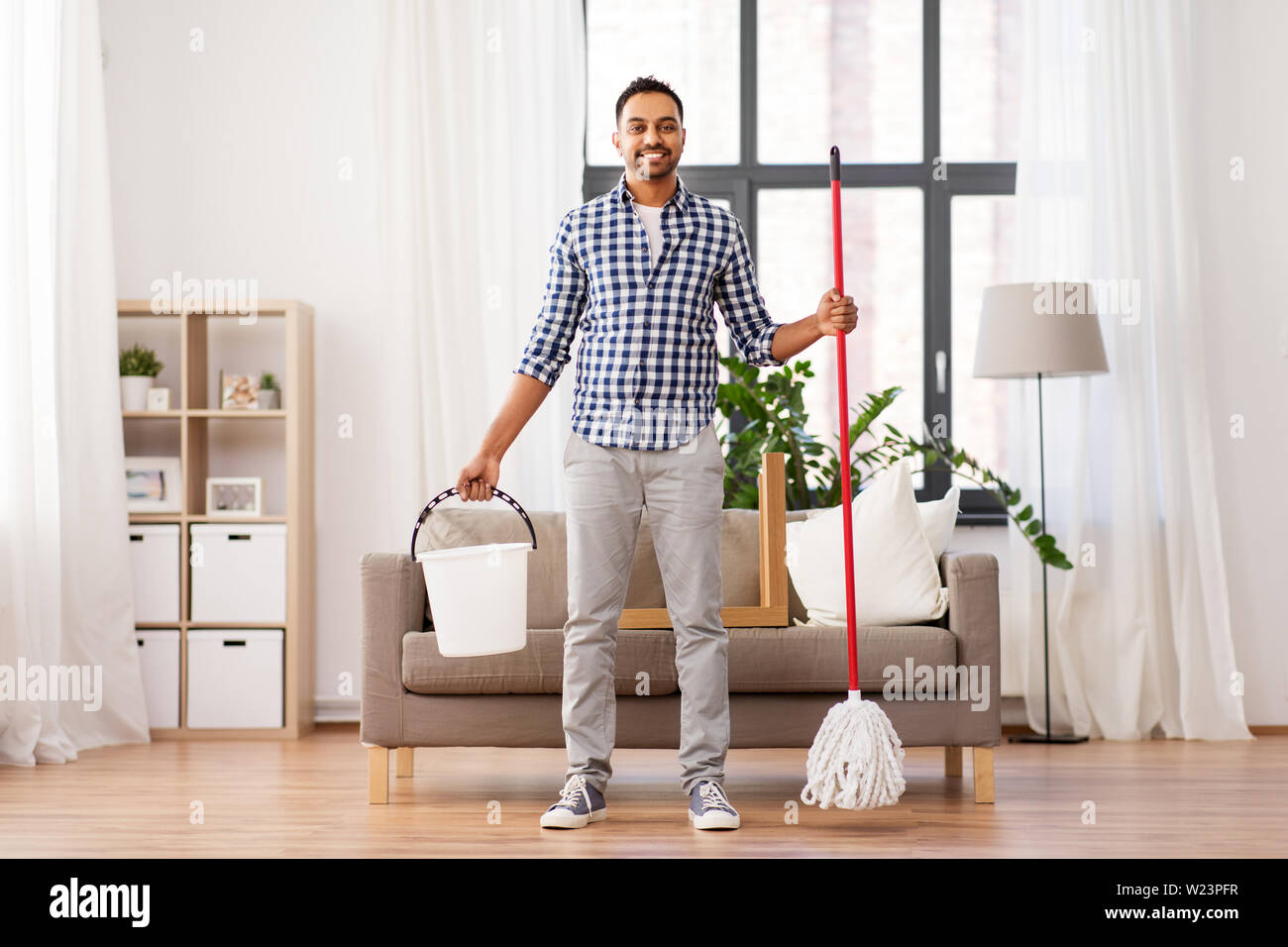 Uomo indiano con mop e la benna pulizia a casa Foto Stock