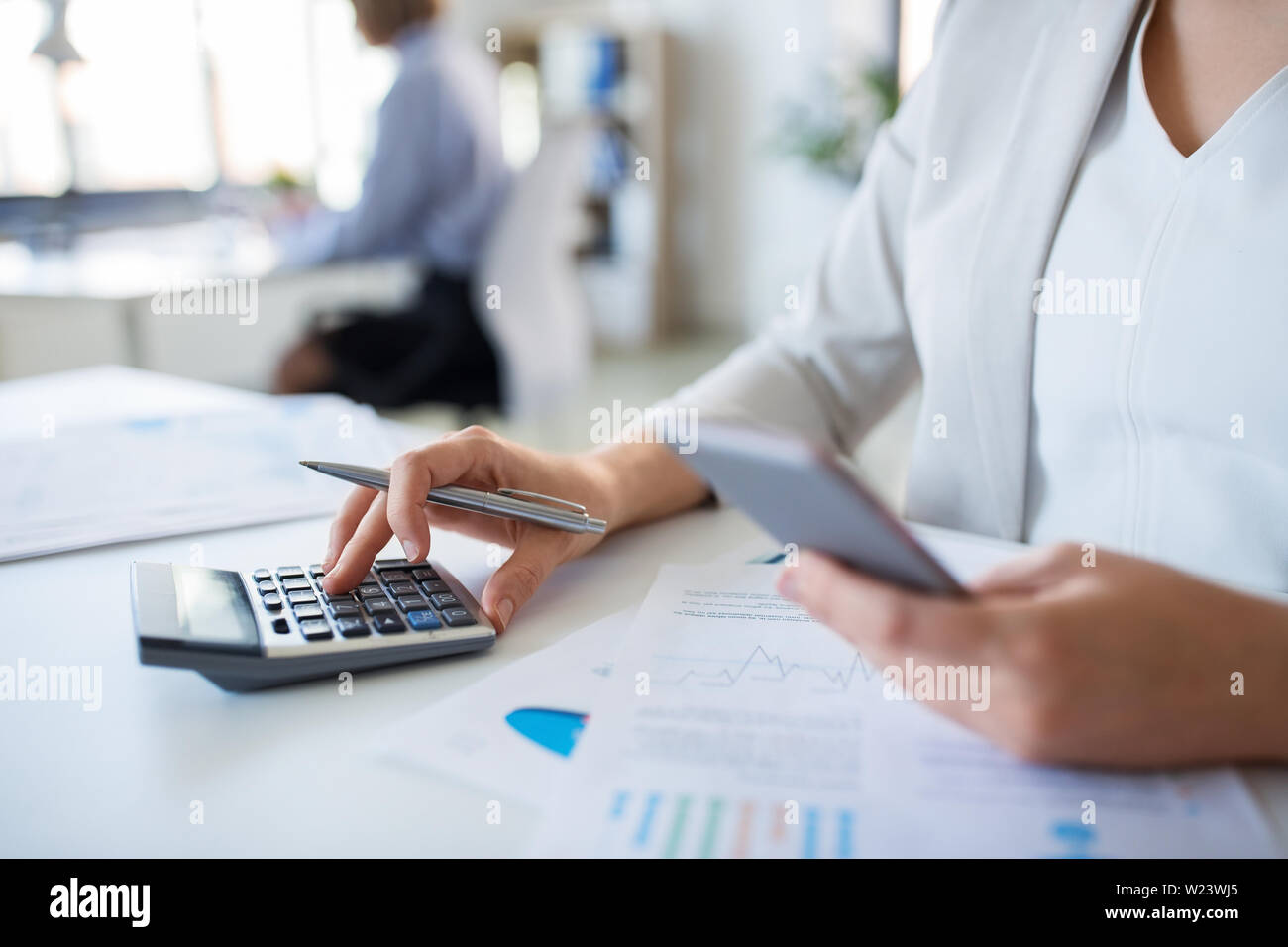 Imprenditrice con la calcolatrice lavorando in ufficio Foto Stock