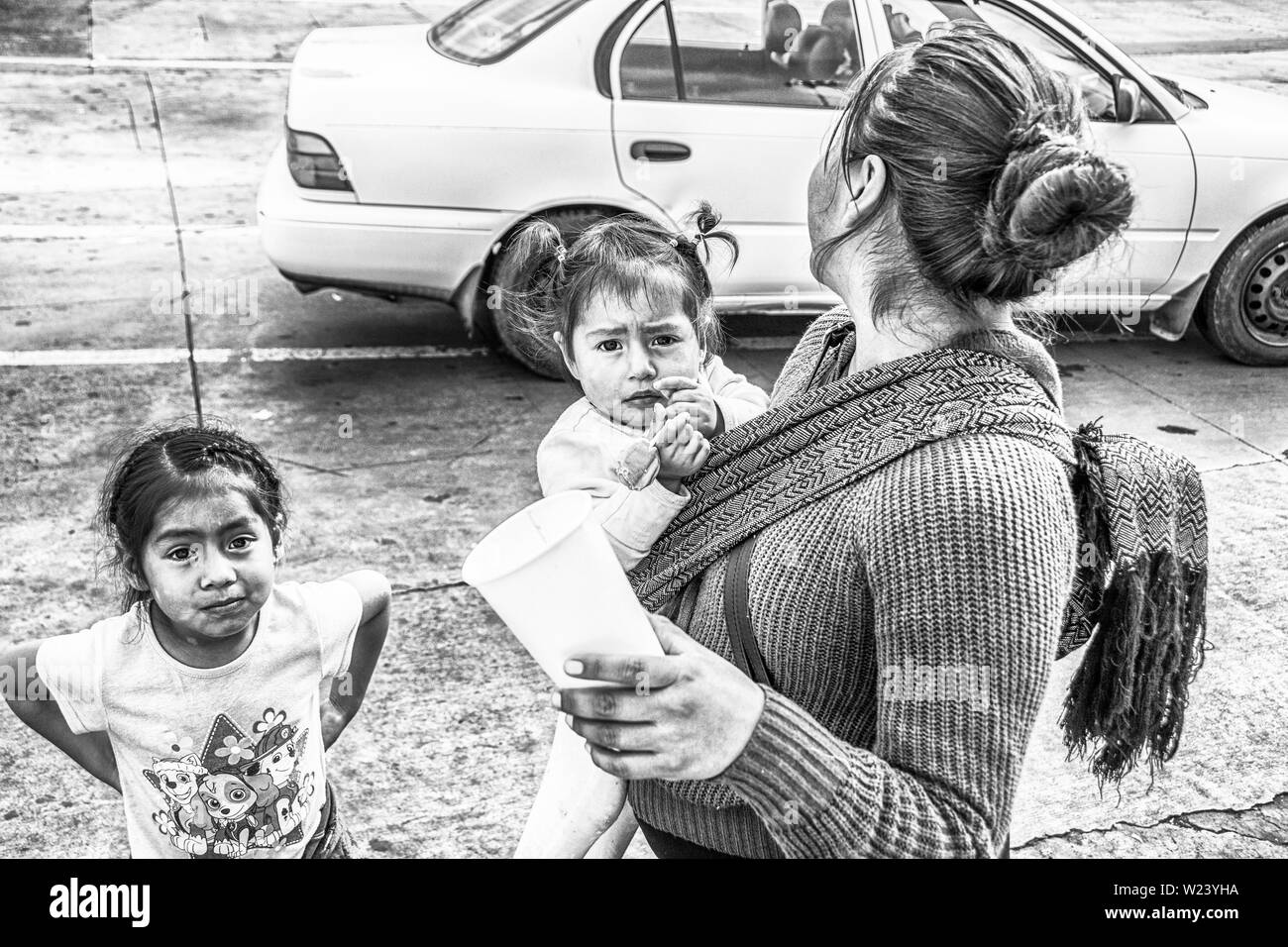 Una donna e i suoi due figli mendicare; al San Ysidro, California e Tijuana, Mexio valico di frontiera; Stati Uniti e Messico. Foto Stock
