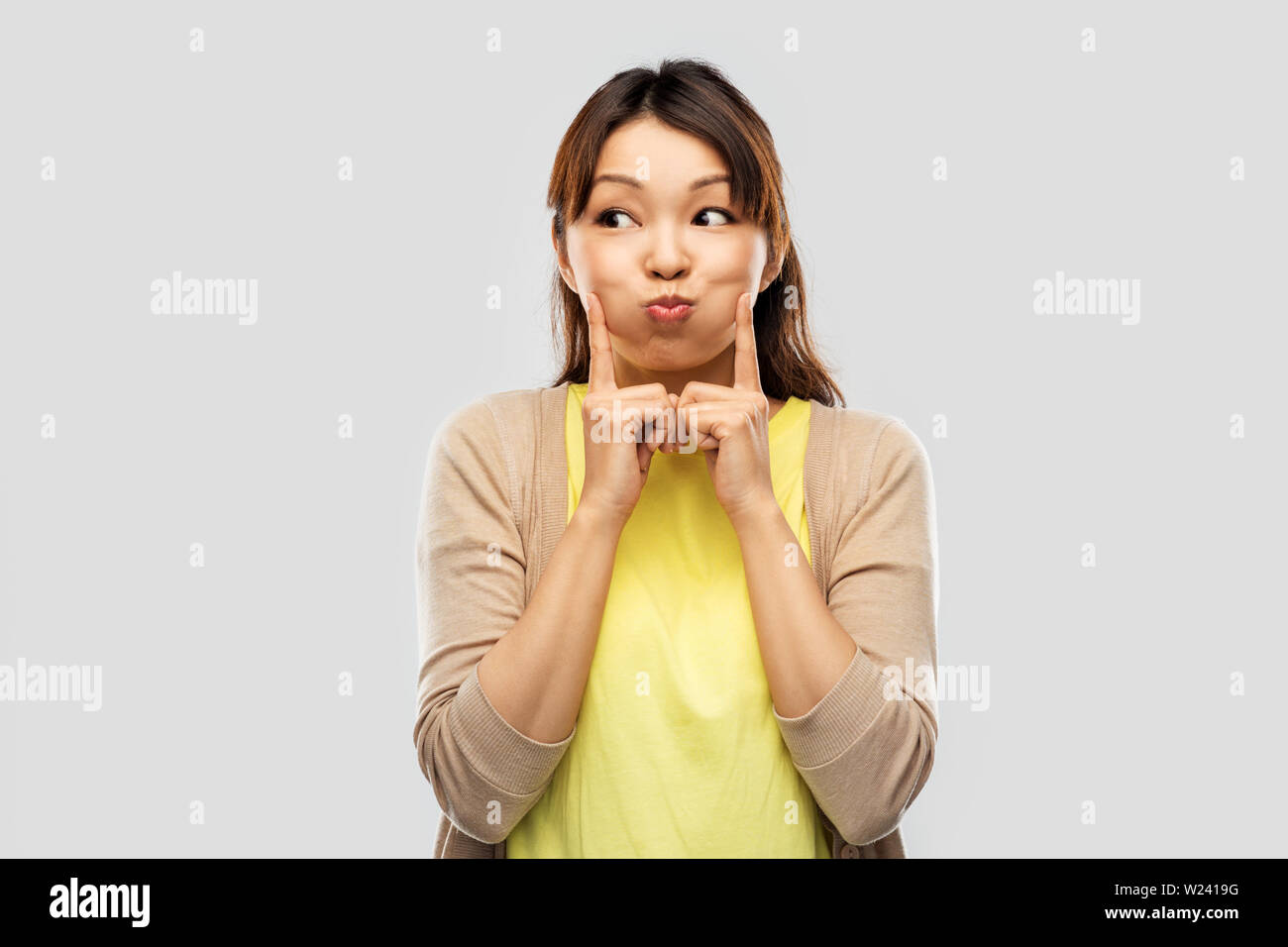 Sorridente donna asiatica rendendo volti e divertirsi Foto Stock