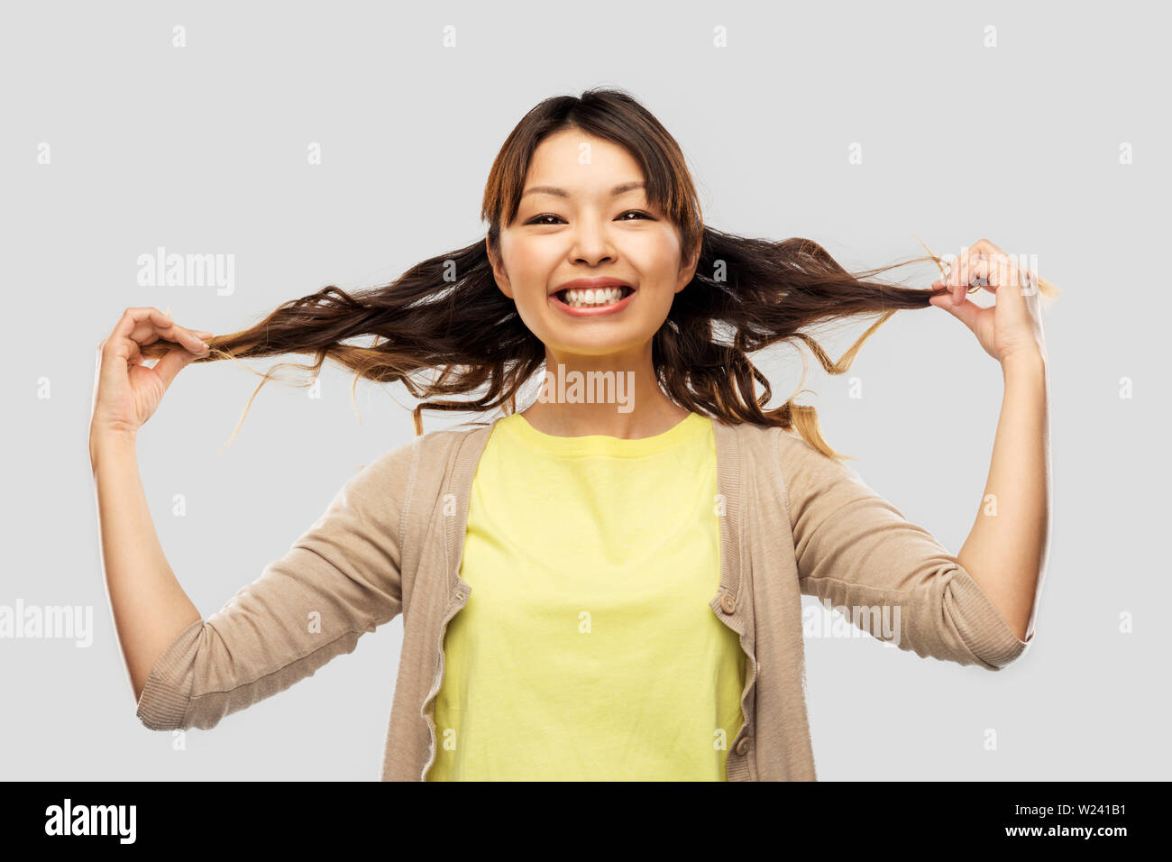 Felice donna asiatica con la piegatura dei capelli Foto Stock