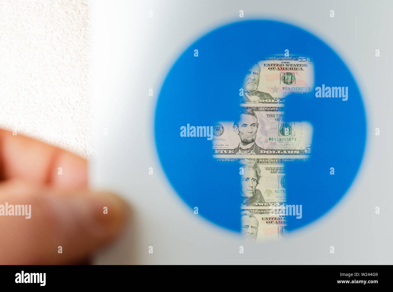 Dollaro visto attraverso il logo trasparente di Facebook su una brochure stampata. Foto concettuale per Facebook Libra - nuovo facebook denaro. Foto Stock