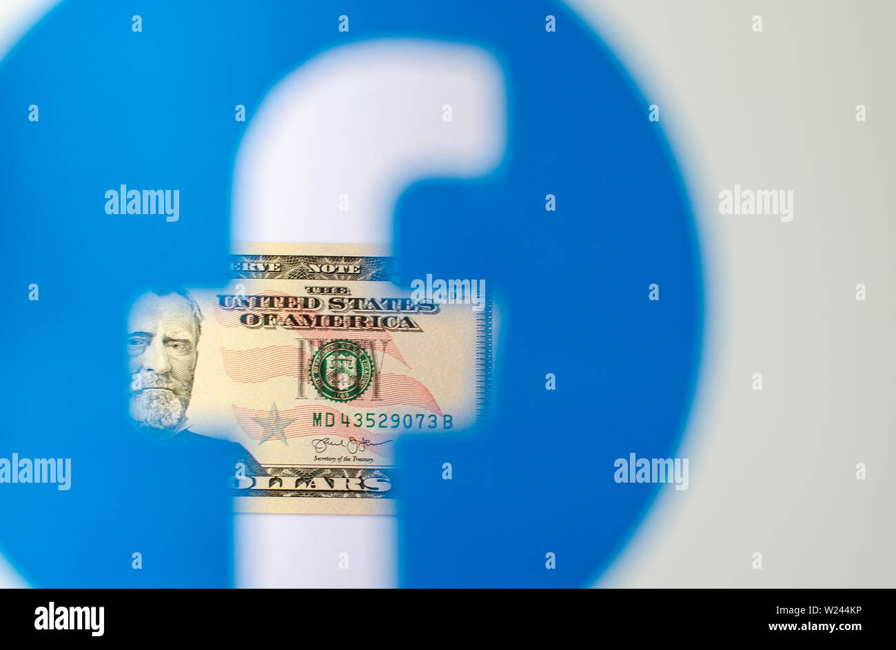 Dollaro visto attraverso il logo trasparente di Facebook su una brochure stampata. Foto concettuale per Facebook Libra - nuovo facebook denaro. Foto Stock