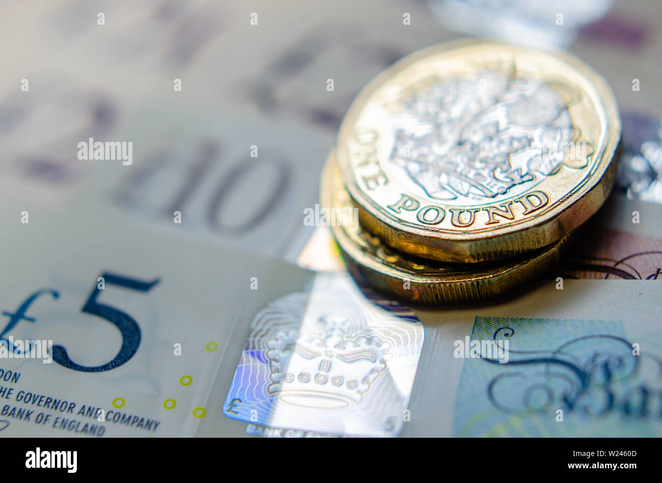 Foto macro di British una libbra di monete sulla parte superiore delle banconote di diverso taglio. Foto Stock