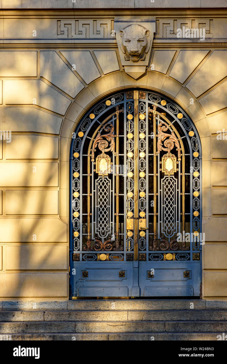 Antico e imponente porta di metallo decorato con i dettagli dorati con ombre e riflessi del sole del tardo pomeriggio Foto Stock