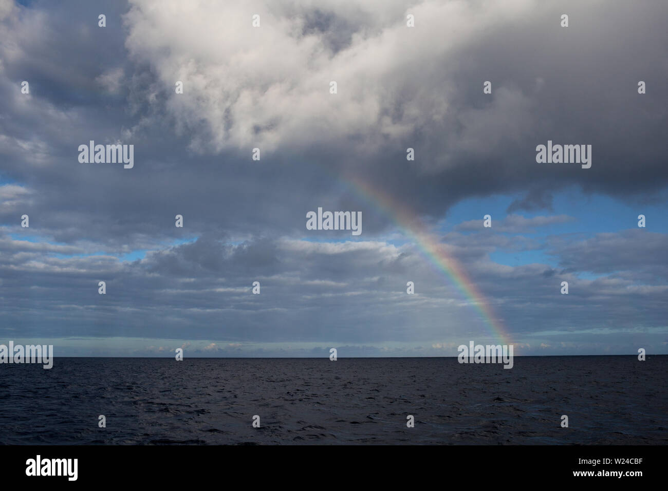 Un arcobaleno appare sopra l'oceano mentre la luce del sole si rifratta attraverso l'umidità atmosferica. Gli arcobaleni sono solo un esempio della bellezza della natura. Foto Stock