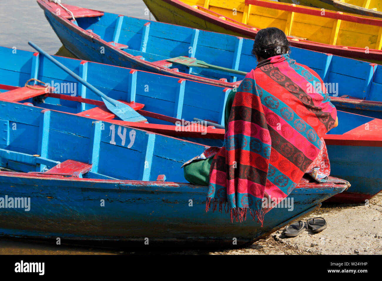 La donna in attesa per i clienti di noleggio in legno colorato per barca crociera sul Begnas Tal (lago Begnas) vicino a Pokhara, Nepal Foto Stock
