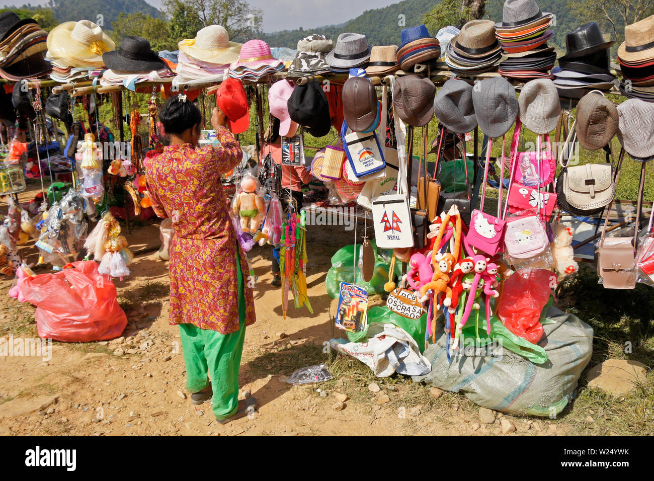 Un fornitore femmina visualizza cappelli, borse, giocattoli e negozio di souvenir in vendita presso Begnas Tal (lago Begnas) vicino a Pokhara, Nepal Foto Stock