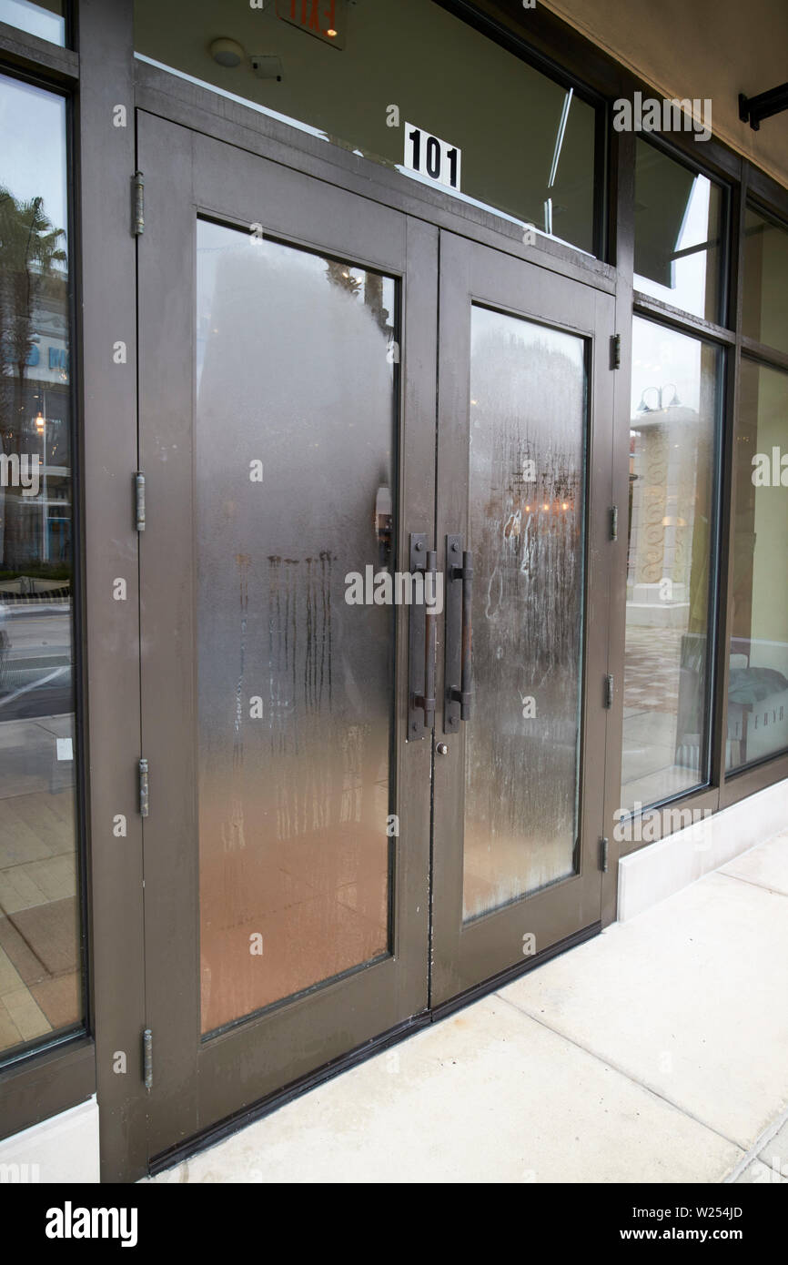 La formazione di condensa sul vetro delle porte di ingresso del negozio in St Johns Town Center Jacksonville in Florida USA la condensazione è causato dalla differenza di h Foto Stock