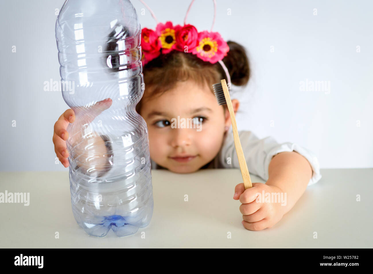 Salvare il mondo libero di plastica. Concetto di consapevolezza della plastica mondo dell'inquinamento, il futuro dei nostri figli. Bambina tenendo il bambù spazzolino da denti e la bottiglia di plastica. Foto Stock