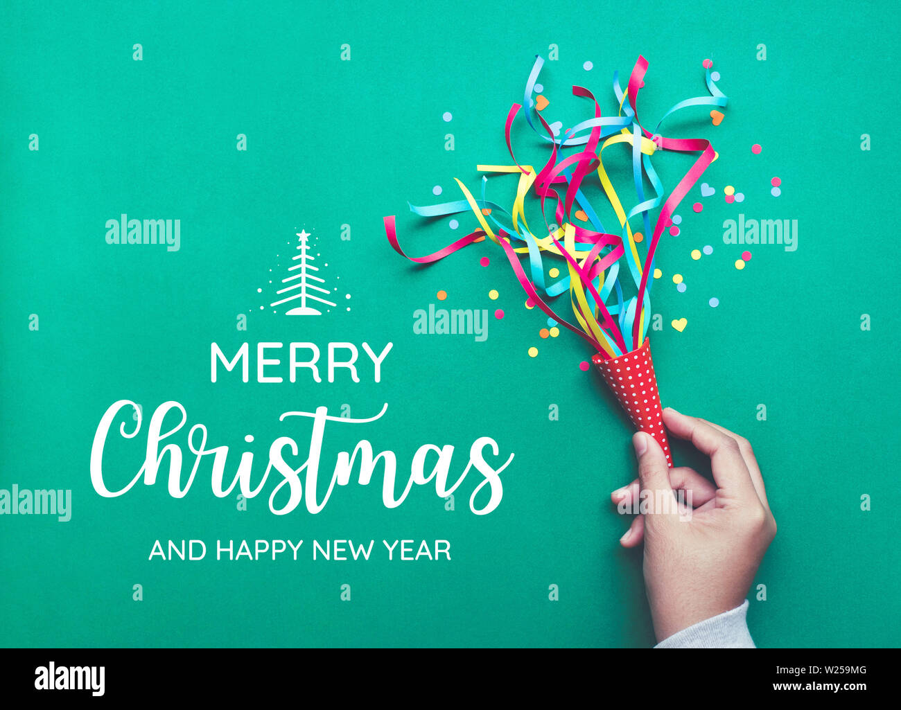 Buon Natale con la mano che regge i coriandoli colorati,streamers.piatto design dei laici Foto Stock
