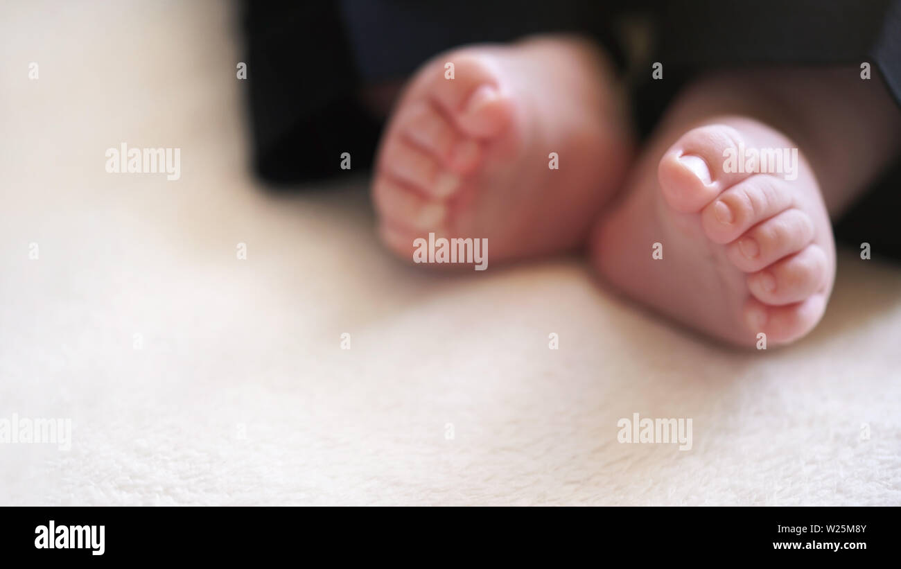 Neonato Bimbo gambe in piccoli pantaloni neri, soft focus foto con dettagli  sui suoi piedi, lo spazio per il testo in basso a sinistra Foto stock -  Alamy