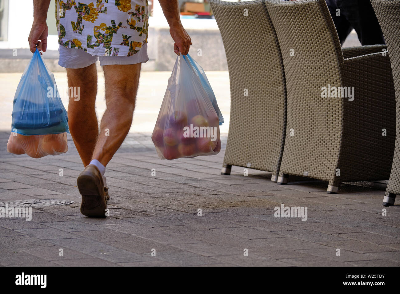 Metà inferiore dell uomo non identificato a piedi con frutta e verdura in più i sacchetti di plastica Foto Stock
