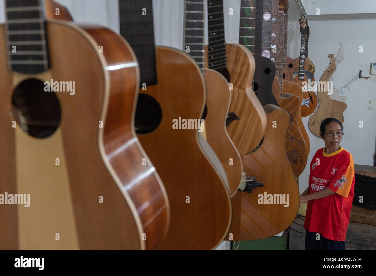 Alcuni customed incompiuta di chitarre e ukuleles appeso sulla camera di finitura alla chitarra classica officina di proprietà di I Wayan Tuges. Foto Stock
